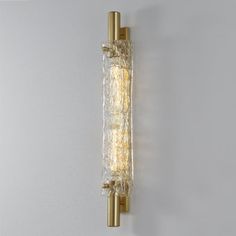 a wall light that is mounted on the side of a wall with glass and brass fixtures