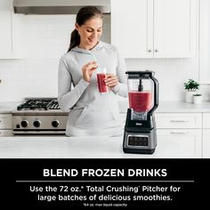 a woman is holding a blender in her hand