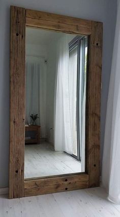 a large mirror sitting on top of a white floor next to a window in a room