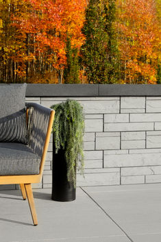 a chair sitting on top of a cement floor next to a wall with trees in the background