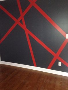 an empty room with red lines painted on the wall and hard wood flooring in front of it