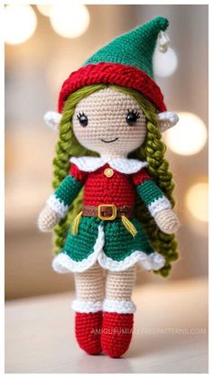 a crocheted elf doll with green hair and red boots, standing on a table