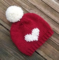 a red and white knitted hat sitting on top of a wooden floor