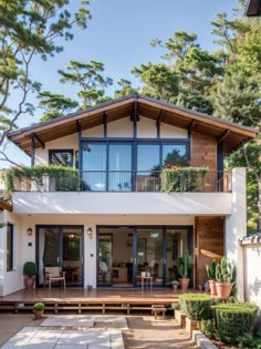 a modern house with large windows and lots of plants on the balcony area in front of it