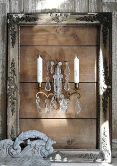 an old wooden frame with two candle holders and some glass beads hanging on the wall