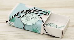 an open gift box with a tag on it and some black and white twine