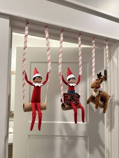 three elfs hanging from the ceiling with candy canes