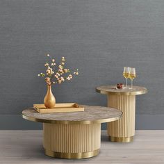 two round tables with vases and wine glasses on each side, against a gray wall