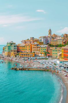 the beach is crowded with people and colorful buildings on it's sides, along with clear blue water