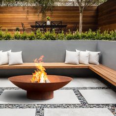 a fire pit sitting on top of a stone floor next to a wooden bench and table