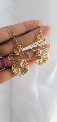 a pair of gold spiral earrings on a person's hand