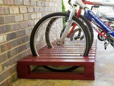 two bikes are parked next to each other on a red bench in front of a brick wall