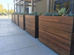 a row of wooden planters sitting on the side of a building