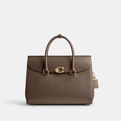 Our Broome has all the effortless cool of its namesake Soho street. The spacious foldover silhouette is crafted of luxe refined leather with a high shine finish and secures with our pushlock “C” closure. Featuring pockets inside and out for easy organization and room for a 16” laptop carry it by hand or use the detachable strap to wear it crossbody. | Coach Broome Carryall Bag 36 - Women's - Brass/dark Stone Coach Work Bags For Women, Latest Coach Handbags, Coach Bags Handbags Coach, Luxury Handbags Coach, Coach Bags 2021, Coach Purse Coach, Coach Tatum Carryall 40, Studio Shoulder Bag Coach, Coach Purses Coach