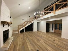 an empty living room with wood floors and chandelier hanging from the rafters