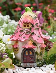 a fairy house with pink flowers surrounding it