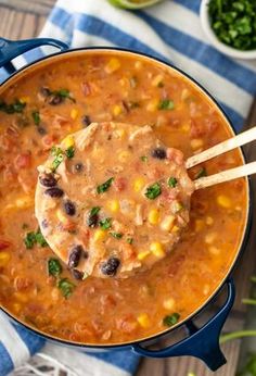 a blue pot filled with mexican bean soup and tortilla chips on the side