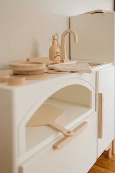 a white toy kitchen with wooden utensils on the counter