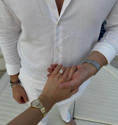 two people holding hands while standing next to each other in front of a white boat