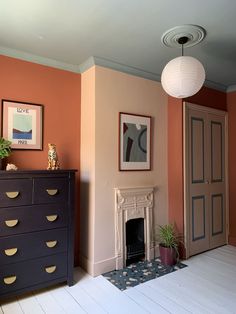 a living room with a dresser, fireplace and pictures on the wall in it's corner