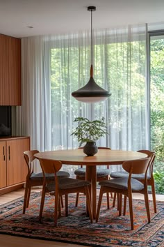 a dining room table with chairs and a potted plant