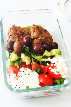 a salad with meatballs and vegetables in a glass dish on a white countertop