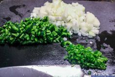 chopped green onions and diced white onions on a cutting board next to a knife