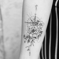 a woman's arm with a compass and flowers tattoo on the left inner forearm