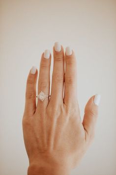 a woman's hand with a white manicure and a diamond ring on it