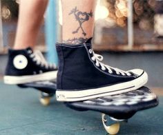 a person with tattoos on their legs riding a skateboard