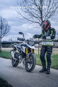 a man in safety gear walking next to a motorcycle