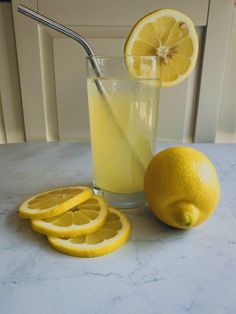 a glass filled with lemonade next to sliced lemons