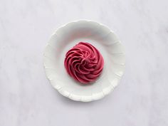 a white plate topped with a pink frosted pastry