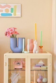 a shelf with vases, candles and other items on it in a living room