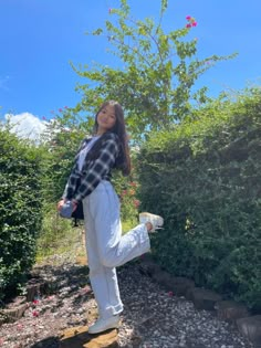 a woman standing on top of a rock next to a bush