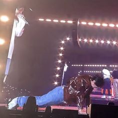 a man laying on top of a stage next to a horse