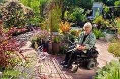 a woman in a wheel chair sitting on a patio surrounded by plants