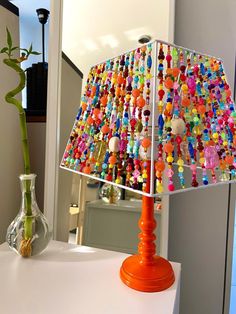 a lamp that is on top of a table with beads hanging from the lampshade