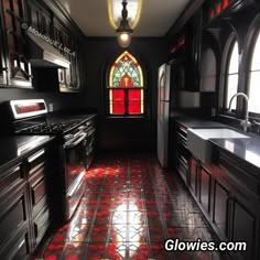 a kitchen with black cabinets and red flooring next to a stained - glass window