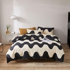 a bed with black and white comforter in a room next to a book shelf