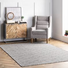 a living room area with a chair, sideboard and rug on the hardwood floor