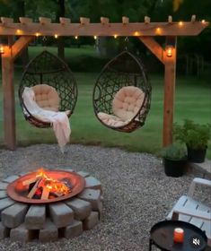 an outdoor fire pit with hammock chairs around it and lights on the side