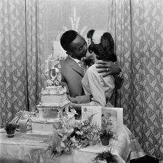 a man and woman kissing in front of a cake