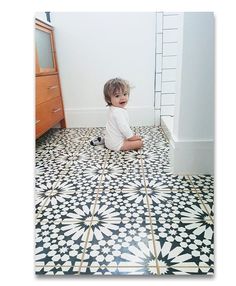 a toddler sitting on the floor in front of a mirror