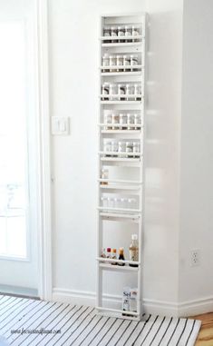 a white shelf filled with lots of bottles on top of a hard wood floor