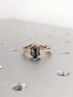 a diamond ring sitting on top of a silver surface with drops of water around it