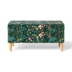 an upholstered footstool with flowers and leaves on it, against a white background