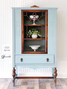 an old china cabinet painted blue with white flowers in the glass front and wood trim