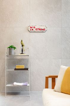 a white chair sitting in front of a shelf with books on it and a yellow pillow