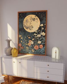 a painting on a wall next to a dresser with flowers and a vase in front of it